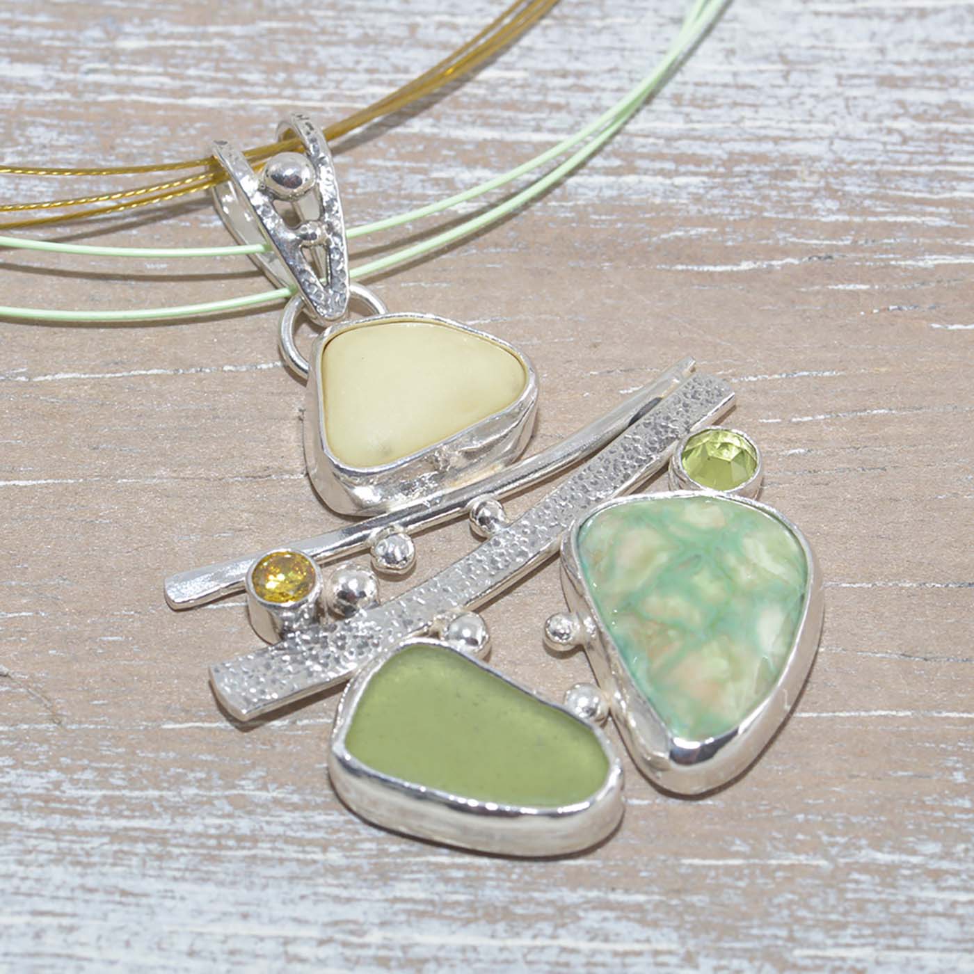 Sea glass and vitreous enamel pendant necklace in a hand crafted setting of sterling silver accented with semi-precious gemstones. (N619)