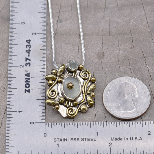 Decorative necklace with gold and silver elements next to a ruler and quarter for scale on a gray surface.