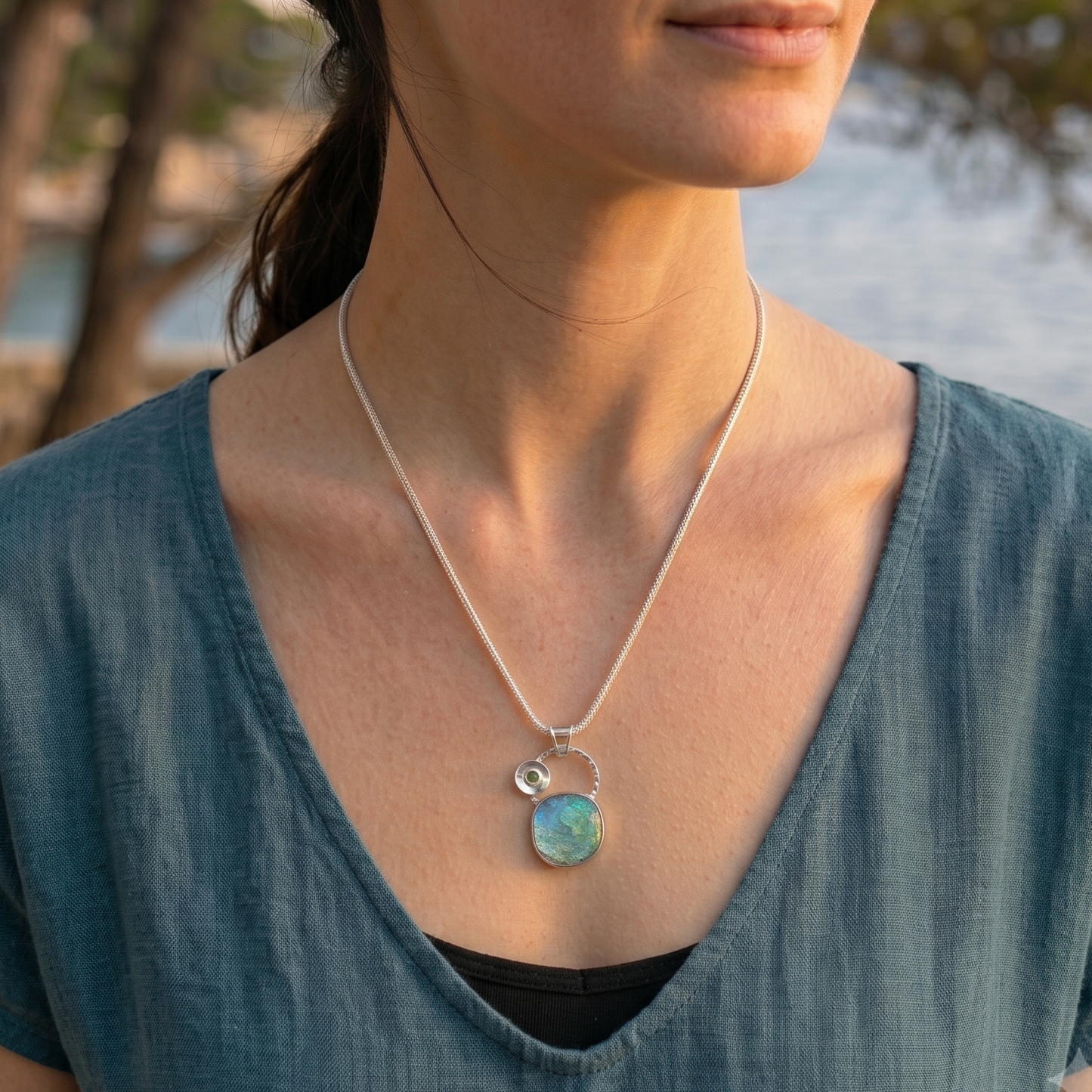Woman wearing a necklace with a pendant by a body of water