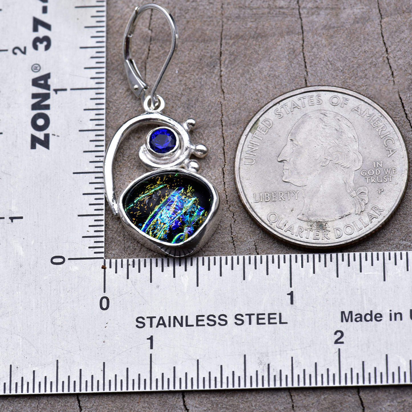 Dichroic glass dangle earring beside a ruler and a quarter, measuring about 1½ inches from ear wire to bottom