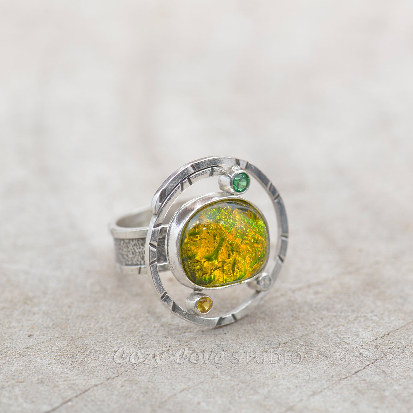 Dichroic glass ring in tones of green and yellow in a hand crafted setting of sterling silver. (R700)