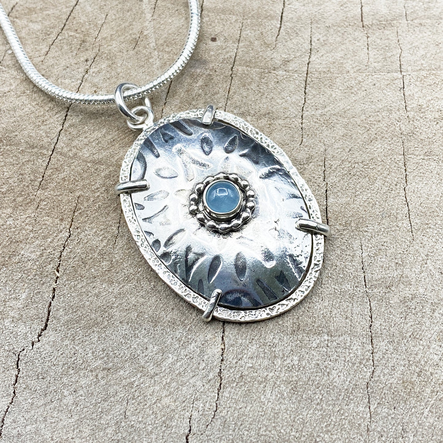 Framed sterling silver pendant necklace accented with an aquamarine cabochon. (N826)
