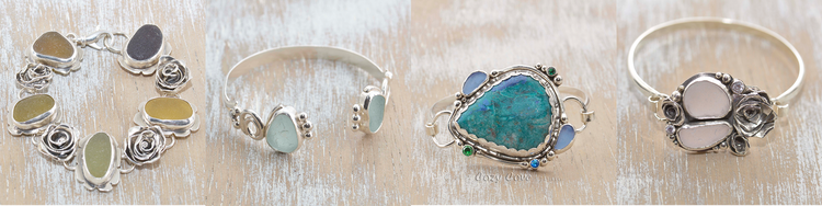 Handmade sterling silver bracelets and cuffs set with sea glass and turquoise, on whitewashed wood.