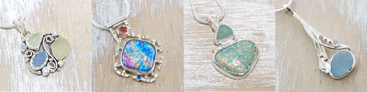 Four handmade silver pendants — two dichroic glass, two sea glass — on whitewashed wood.