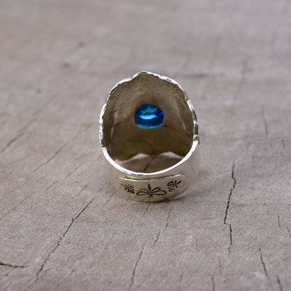 Back of silver ring with a blue gemstone on a wooden surface