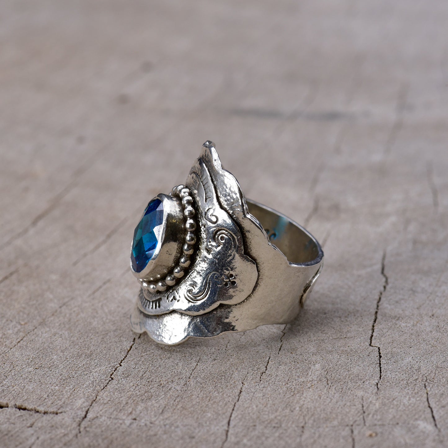 Silver ring with blue gemstone on a wooden surface
