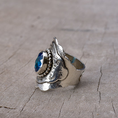 Silver ring with blue gemstone on a wooden surface