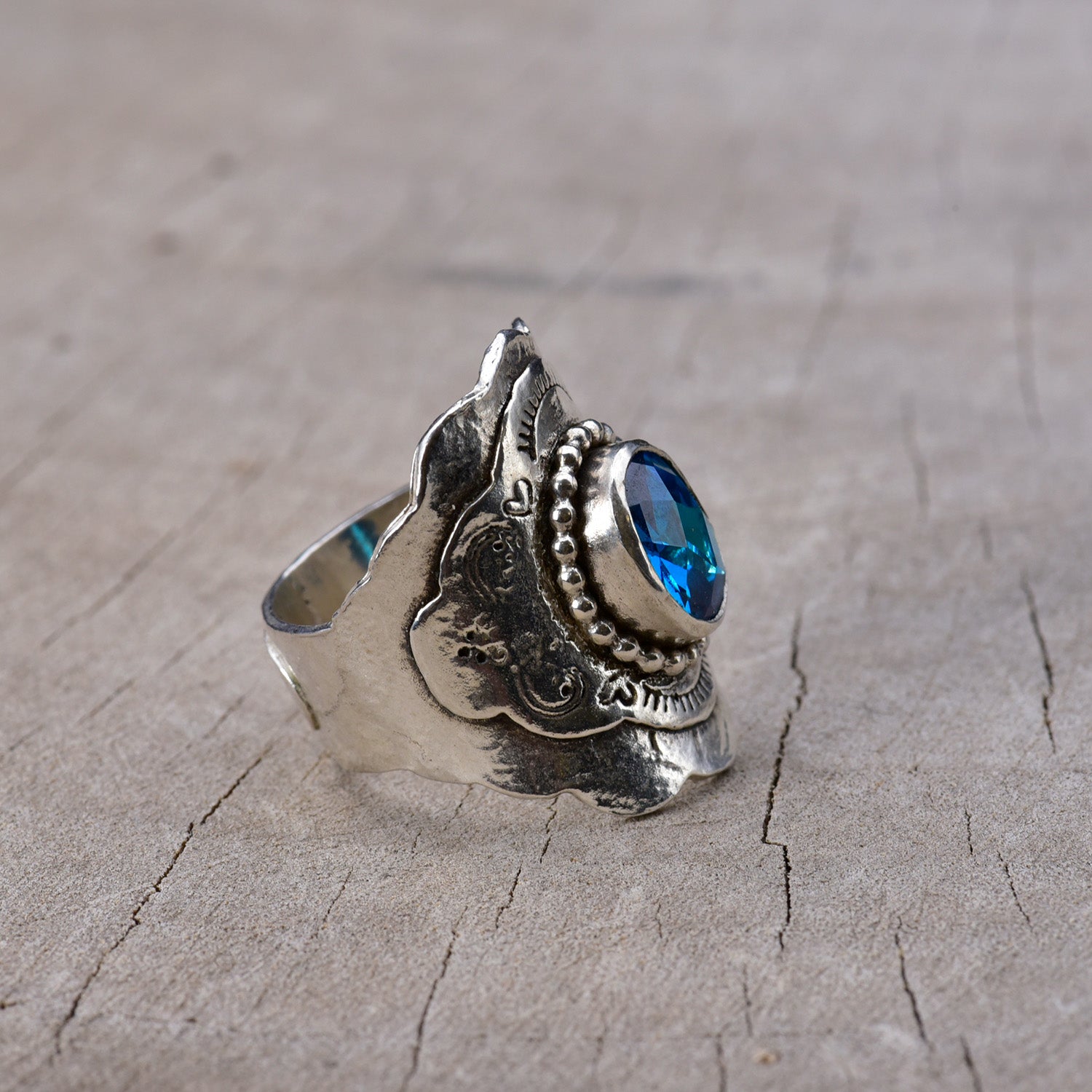 Silver ring with a blue gemstone on a textured gray surface