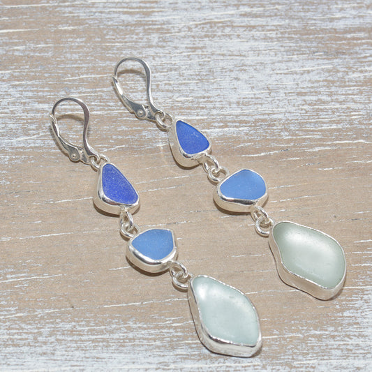 Sea glass dangle earrings in shades of blue in hand crafted settings of sterling silver. (E615)