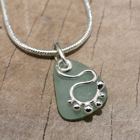 Sea glass pendant necklace accented with a handcrafted sterling silver charm. (N814)