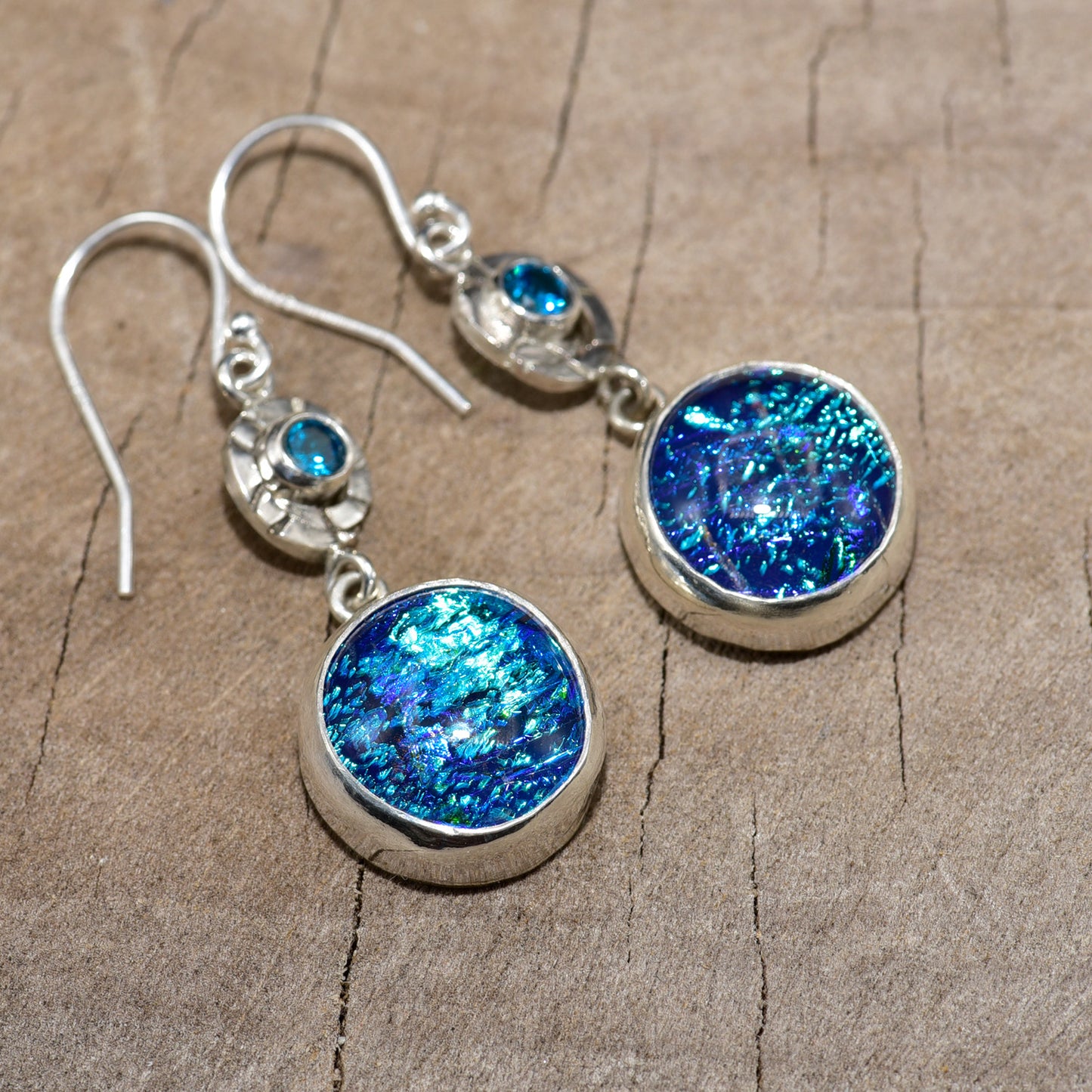 Flashy blue dichroic glass earrings in hand crafted settings of sterling silver. (E820)