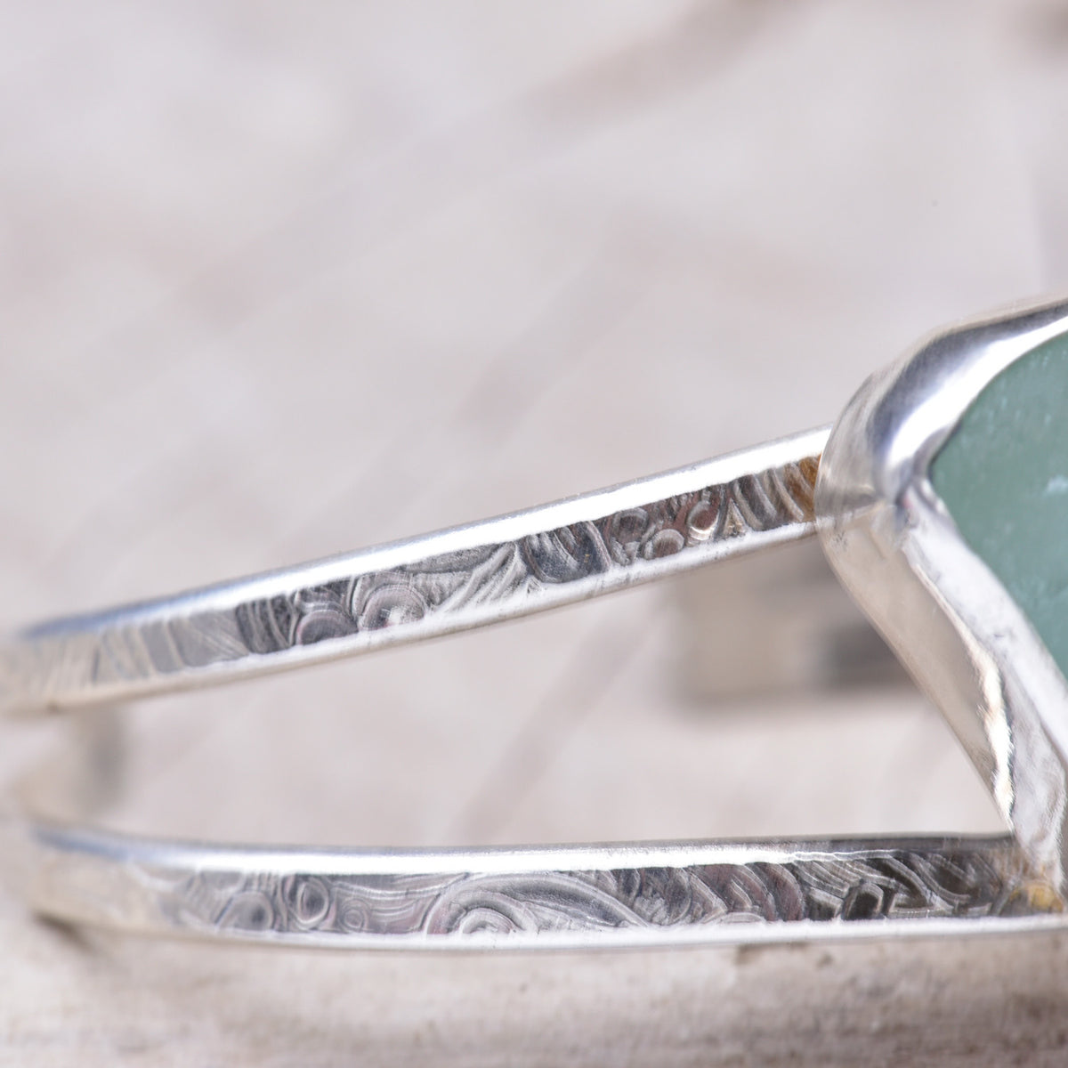 Close-up of the double cuff bands showing the hand pattern-rolled floral scrollwork in the sterling silver