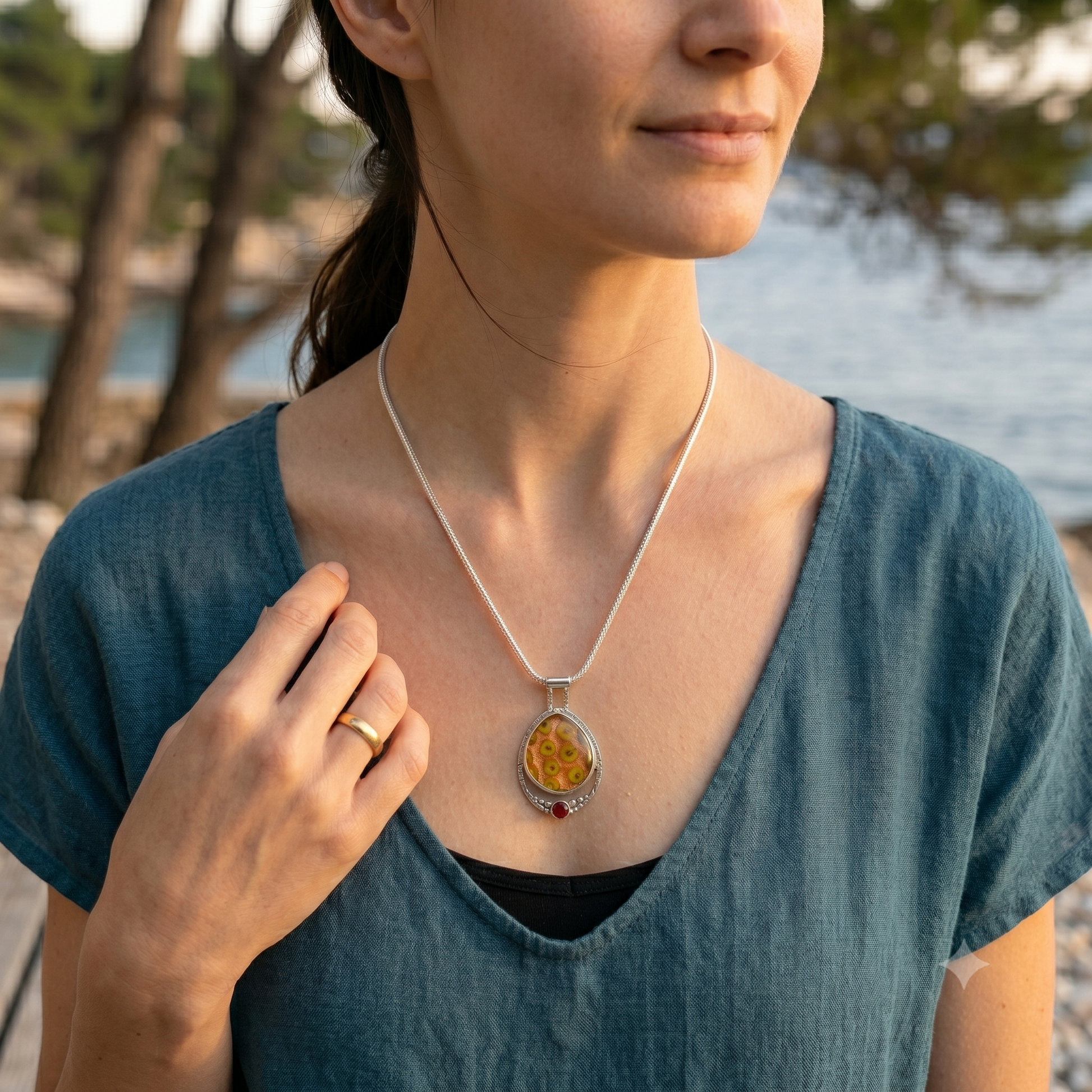 Woman wearing a necklace with a pendant by a body of water