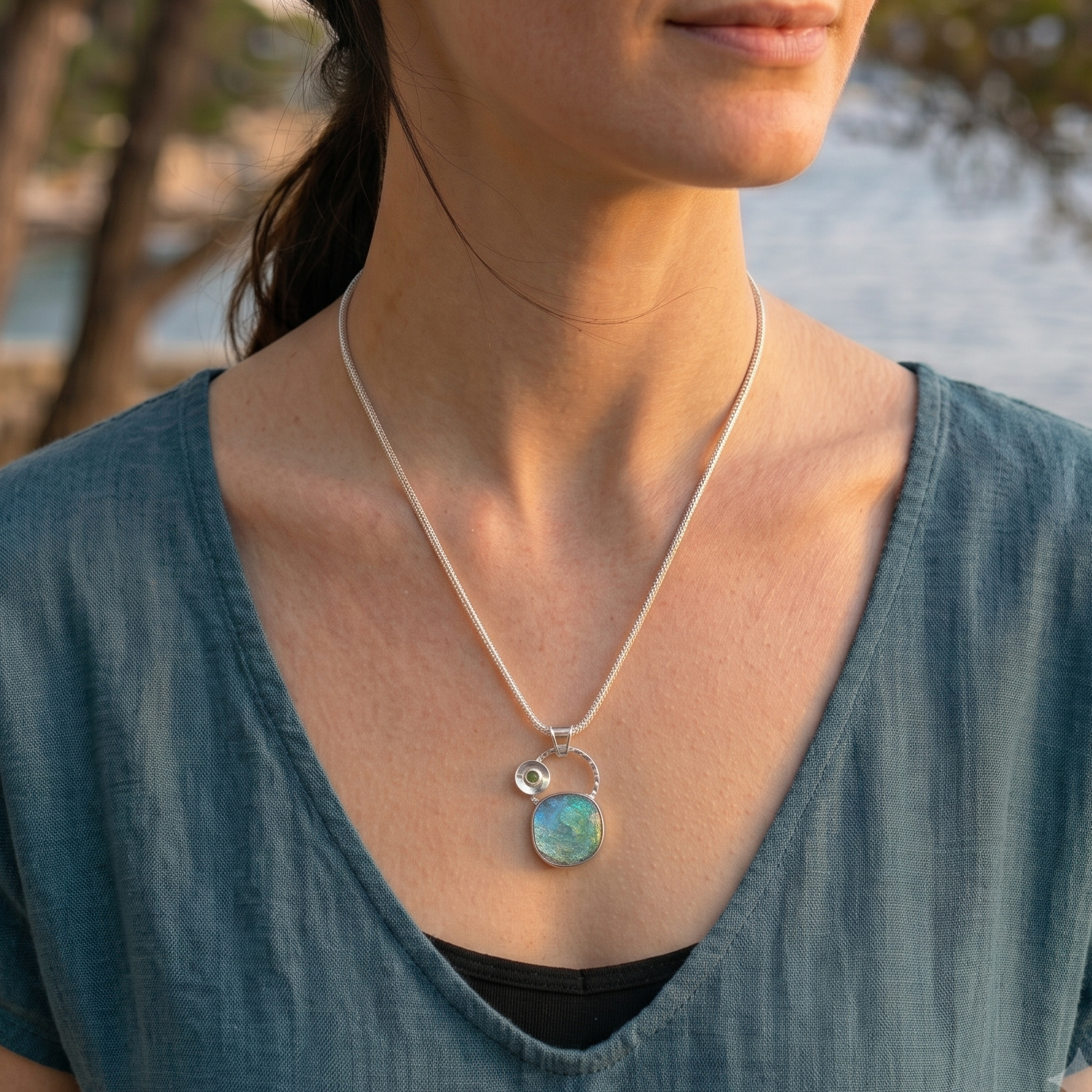 Woman wearing a necklace with a pendant by a body of water