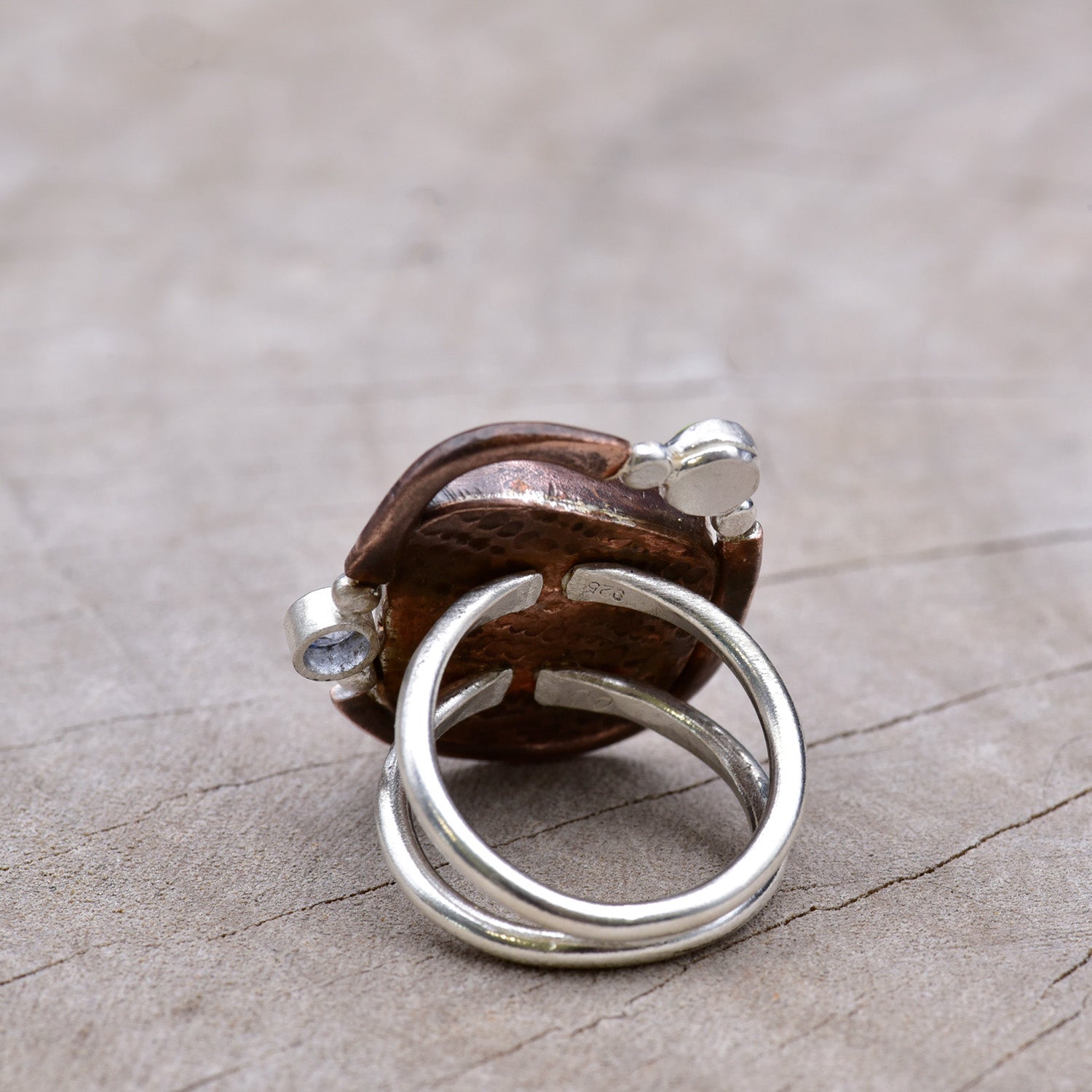 Silver ring with a wooden element on a textured surface