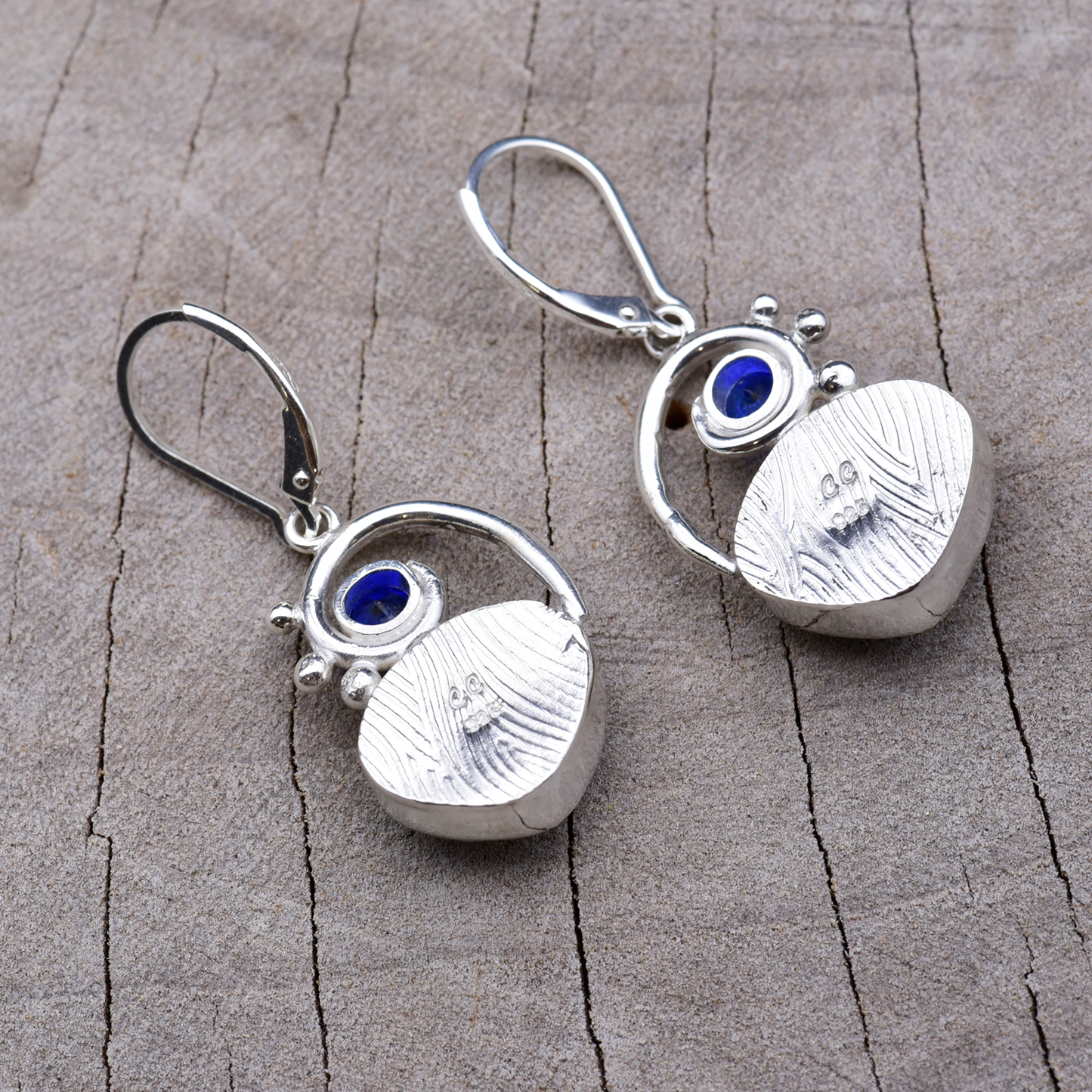 Backs of the sterling silver earrings showing the embossed bezel texture and the CC maker's mark