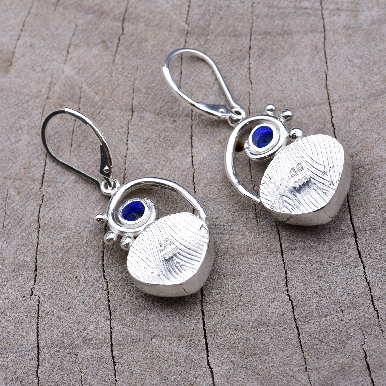 Backs of the sterling silver earrings showing the embossed bezel texture and the CC maker's mark