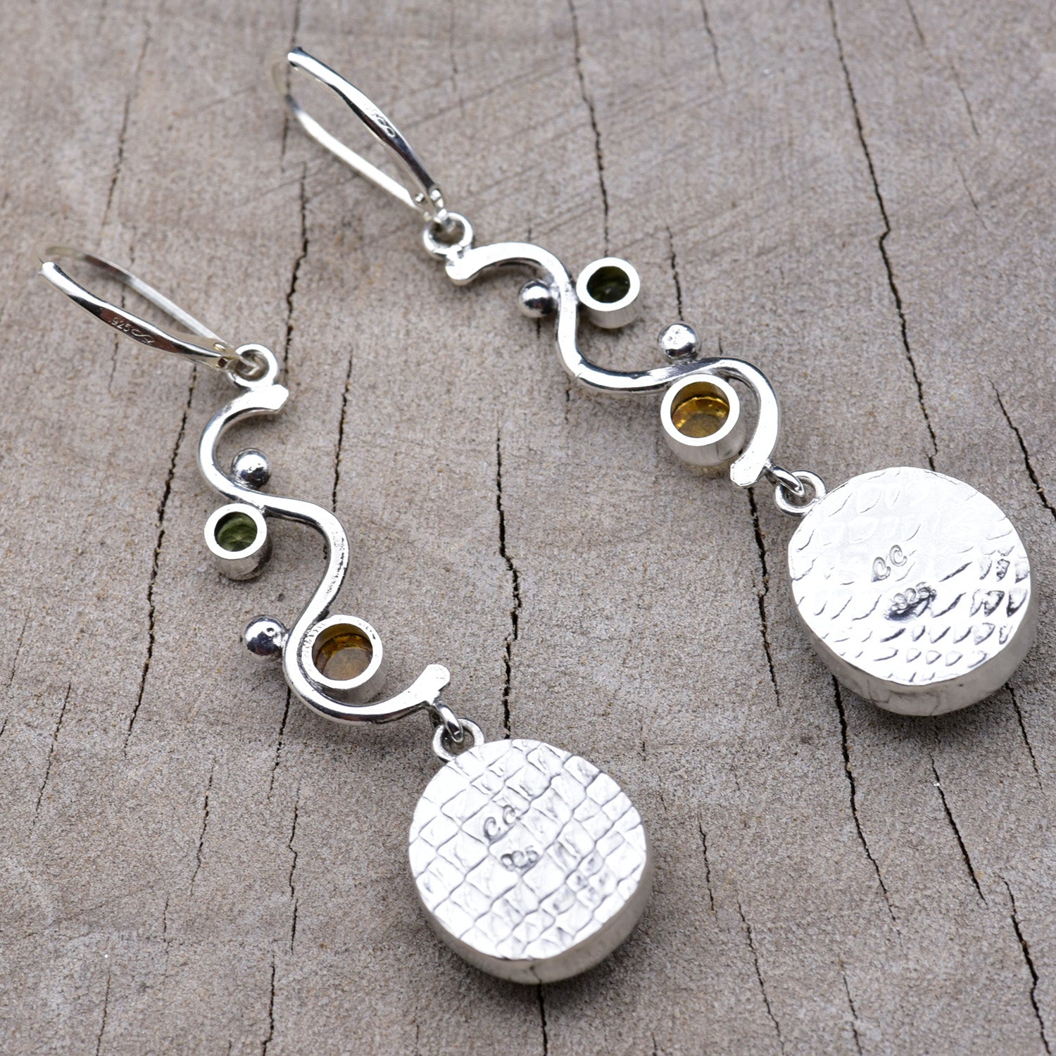 Backs of the earrings showing the pattern-rolled embossed silver bezels with the CC maker's mark and 925 sterling hallmark