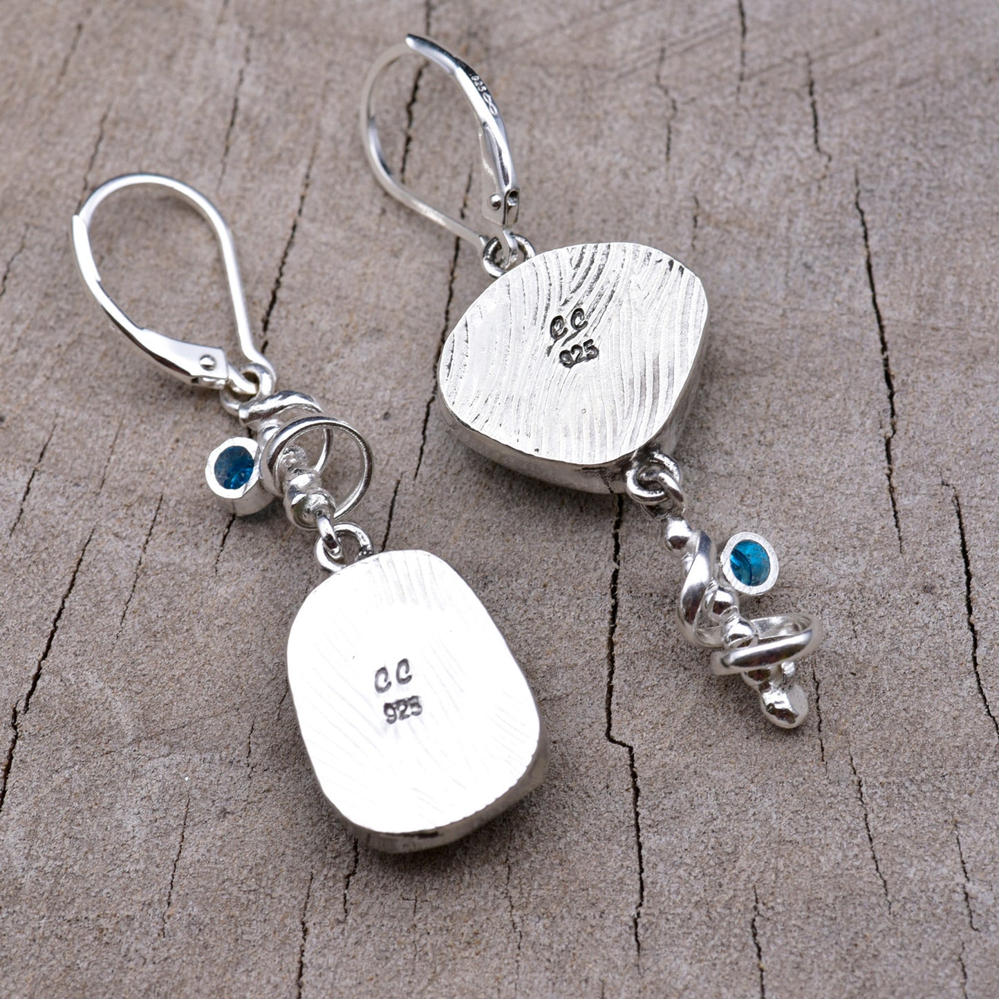 Backs of the earrings showing the pattern-rolled silver bezels stamped with the CC maker's mark and 925 sterling hallmark