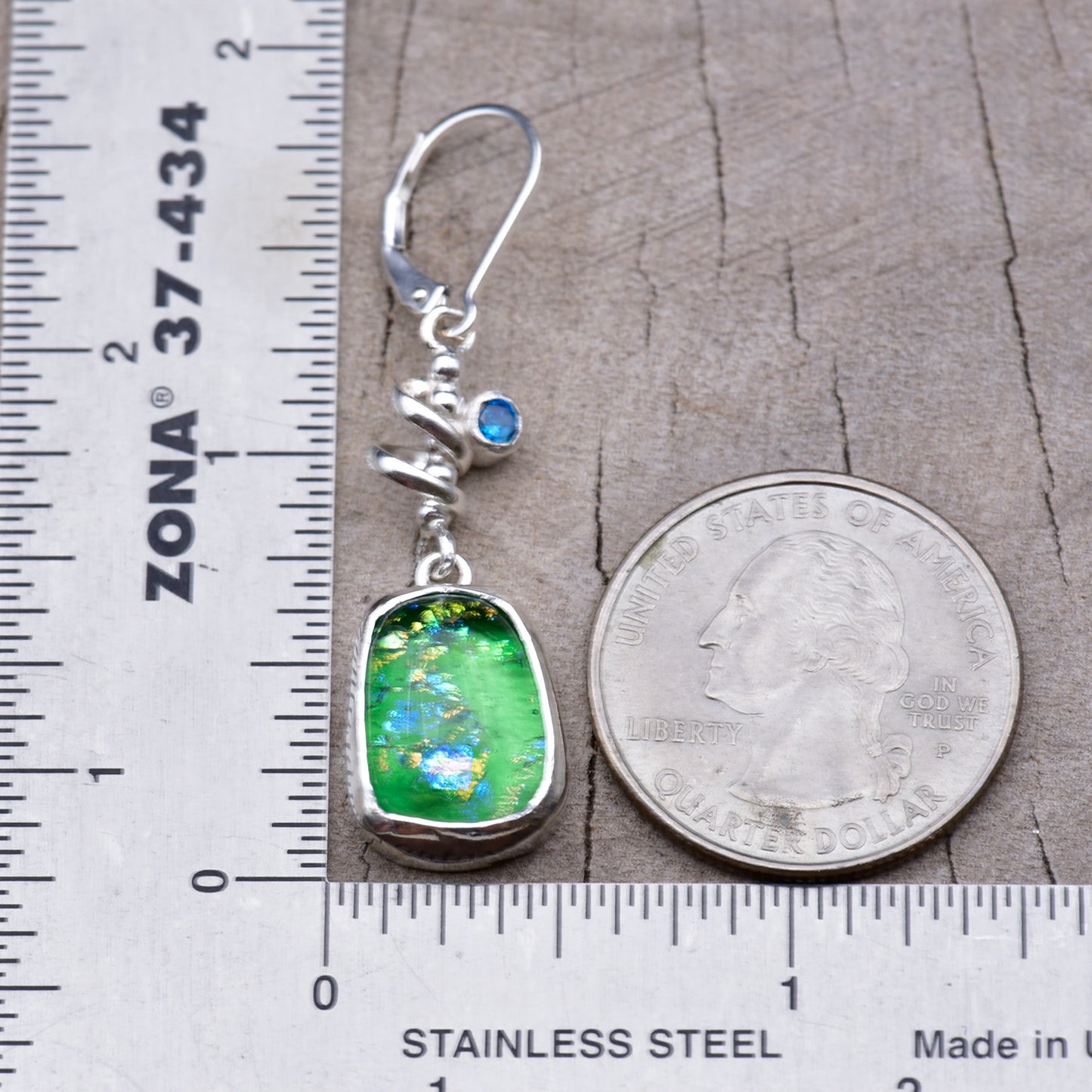 One earring beside a ruler and a quarter, measuring about 1 3/4 inches from the top of the ear wire to the bottom of the glass