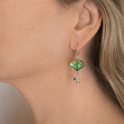 Spring green dichroic glass asymmetric dangle earring worn on the ear, the glass at the top and a silver spiral swinging below