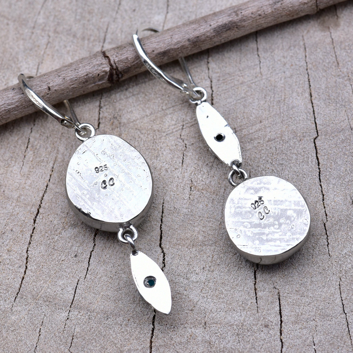Backs of the earrings showing the pattern-rolled silver bezels stamped with the CC maker's mark and 925 sterling hallmark