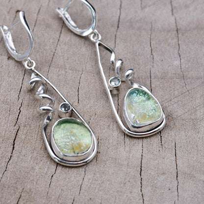 Handmade sea green and aqua dichroic glass dangle earrings in open teardrop Argentium sterling silver frames with corkscrew spirals and aqua cubic zirconia accents, on weathered wood