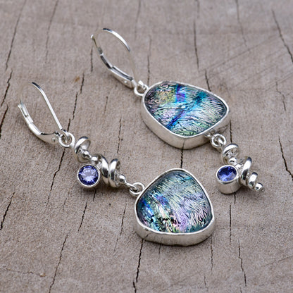 Handmade asymmetric dichroic glass dangle earrings with teal, blue and lavender streaked glass, Argentium sterling silver spiral dangles and violet blue cubic zirconia accents, on weathered wood