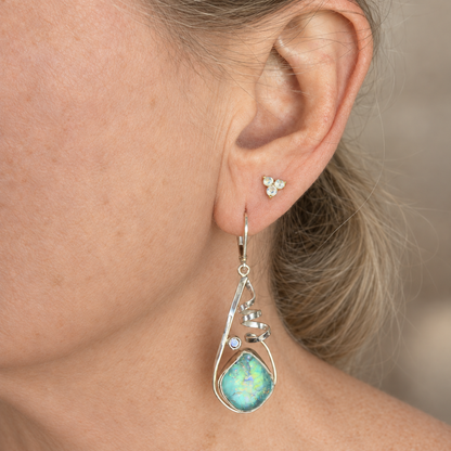 Aqua dichroic glass earring with a silver spiral frame worn on the ear, showing how the long drop hangs