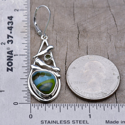 Sky blue and lime green fused glass earring beside a ruler and a quarter for scale, measuring about 2 inches long