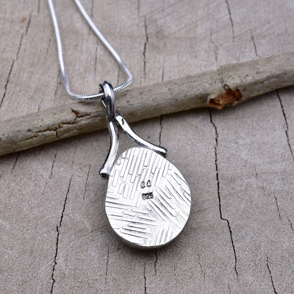 Embossed back of the gold and aqua teardrop dichroic glass pendant showing the textured Argentium silver, CC maker's mark and 925 hallmark