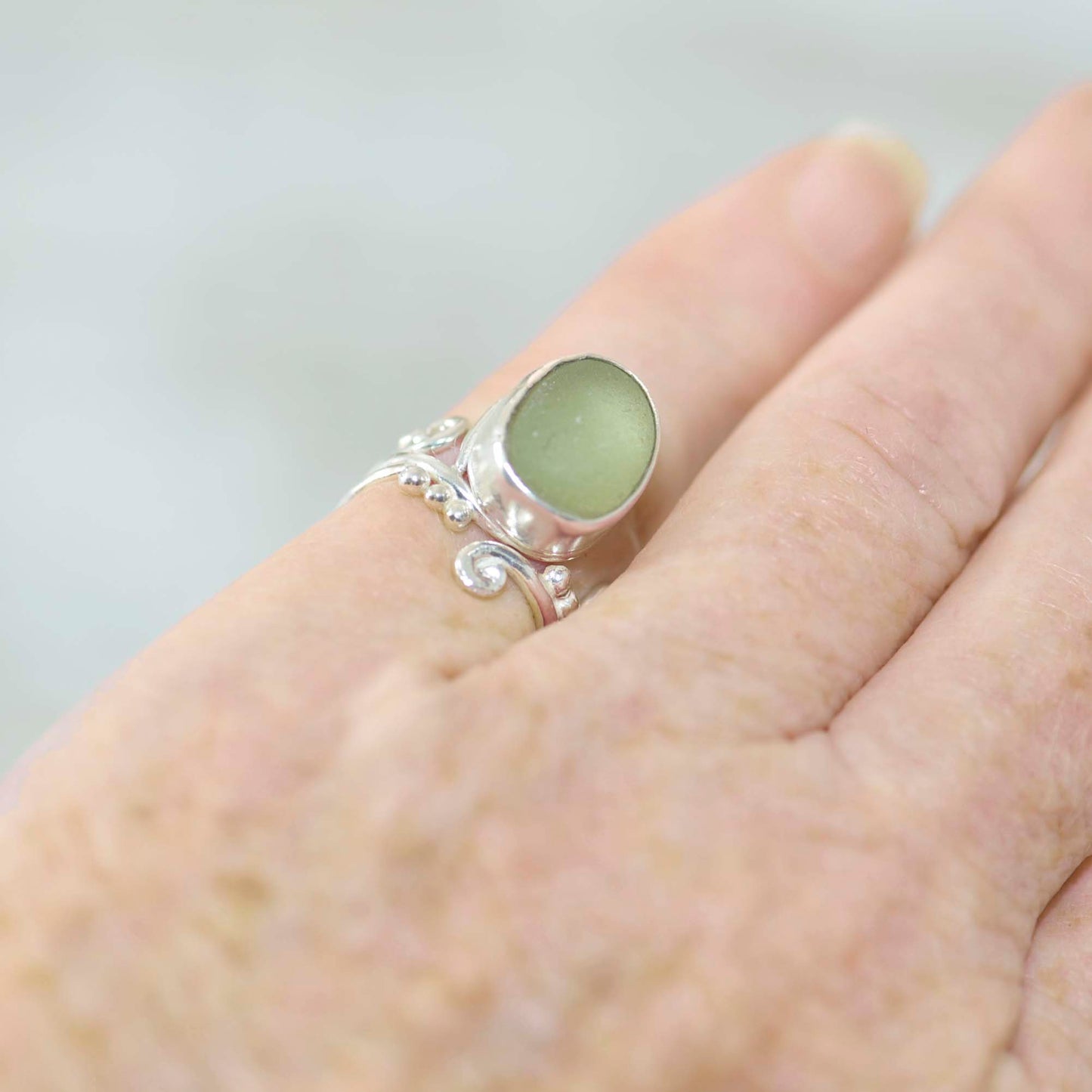 Green sea glass ring in sterling silver worn on finger