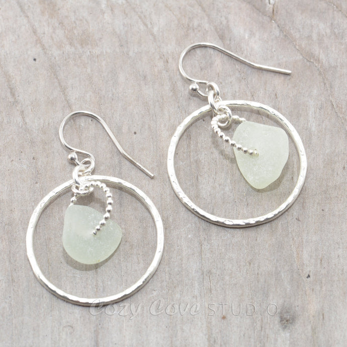 Pale green sea glass earrings encircled by textured hoops of sterling silver.