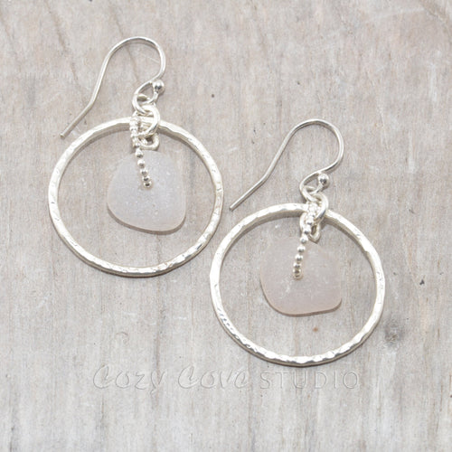 Pale lavender sea glass earrings encircled by textured hoops of sterling silver.