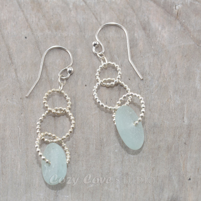 Sea glass dangle earrings on circle of sterling silver beaded wire.