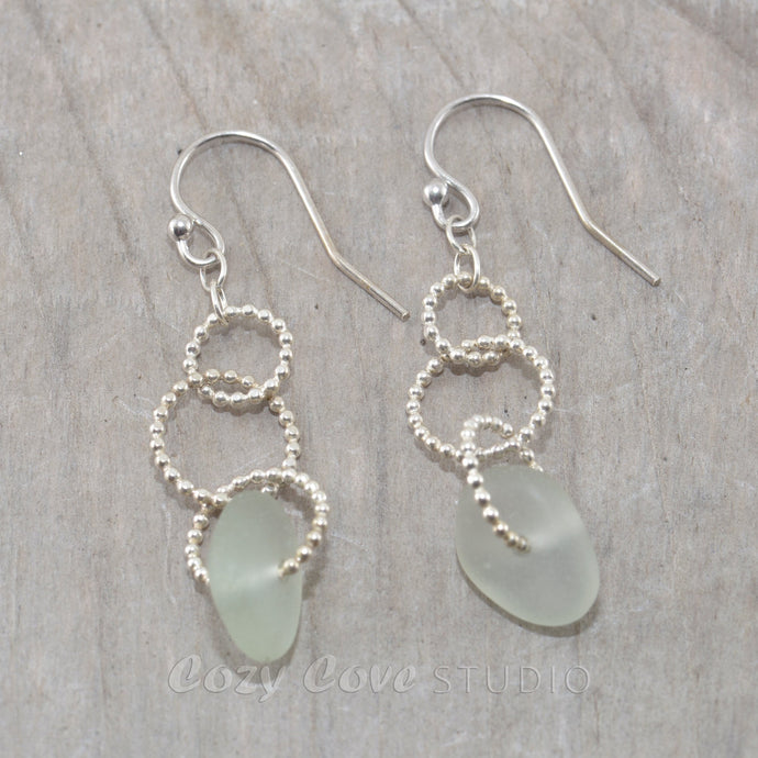 Sea glass dangle earrings on circle of sterling silver beaded wire.