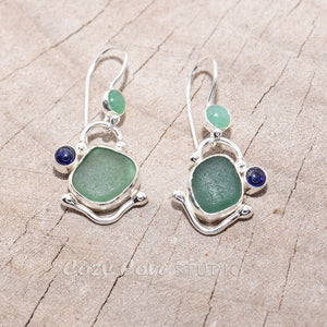 Teal sea glass dangle earrings accented with a sapphire cabochon and citrine cabochon in settings of sterling silver. (E718)