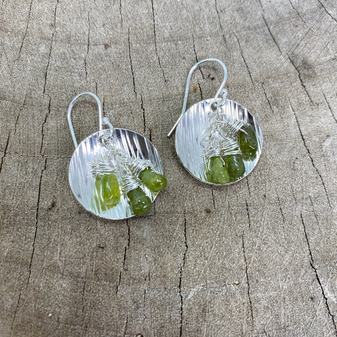 Earrings crafted from disks of hammer textured sterling silver accented with dangles of peridot briolettes (E797)