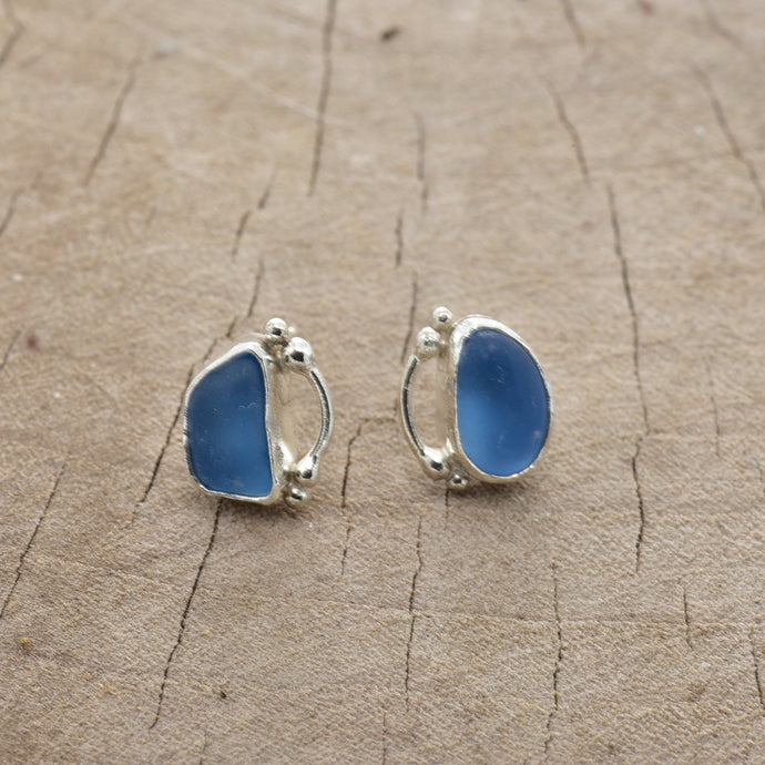 Sea glass earrings of cornflower blue in hand crafted bezel settings of sterling silver. (E803)